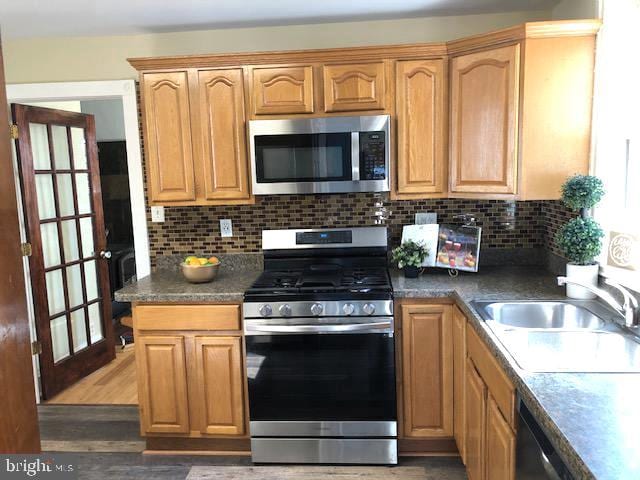 kitchen with stainless steel appliances, dark hardwood / wood-style floors, sink, and tasteful backsplash