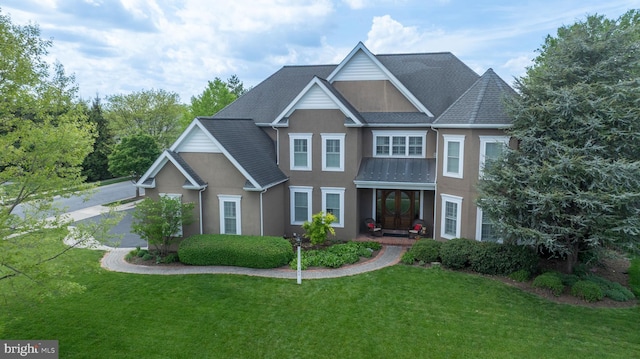 view of front of property featuring a front yard, stucco siding, and a shingled roof