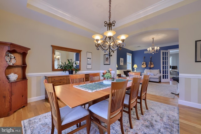 dining area with baseboards, ornamental molding, an inviting chandelier, and light wood-style flooring
