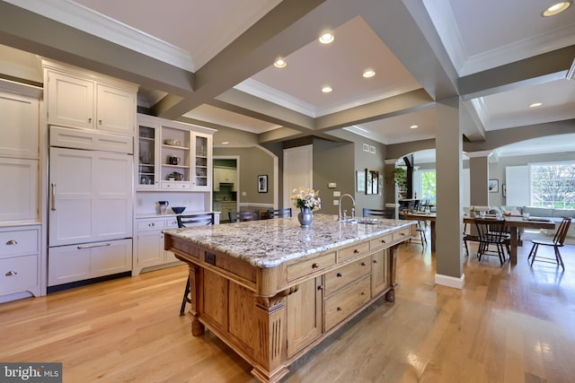 kitchen with open shelves, crown molding, arched walkways, and a sink