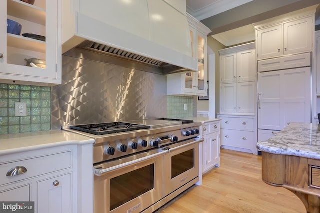 kitchen featuring ornamental molding, custom exhaust hood, light wood-style flooring, white cabinetry, and double oven range