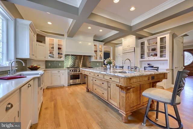 kitchen featuring high quality appliances, light wood-style flooring, an island with sink, and a sink