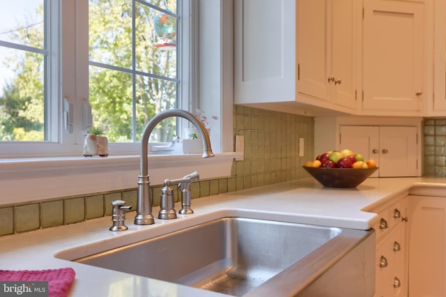 details with light countertops, white cabinets, a sink, and tasteful backsplash