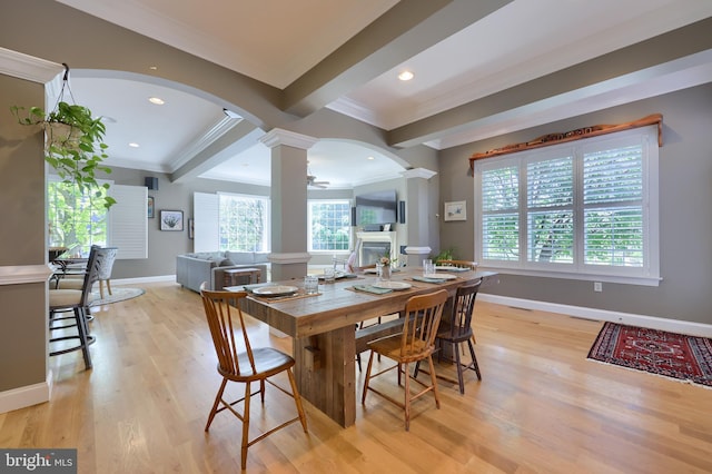 dining space featuring arched walkways, a wealth of natural light, ornamental molding, and decorative columns