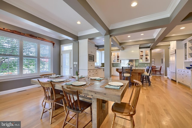 dining room featuring crown molding, light wood-style flooring, baseboards, and a healthy amount of sunlight