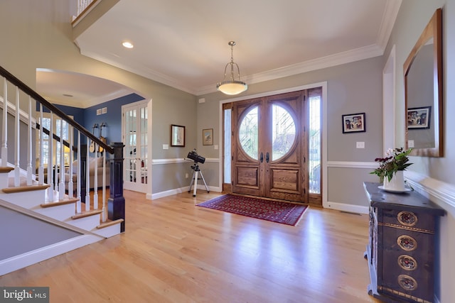 foyer featuring crown molding, stairway, wood finished floors, and arched walkways