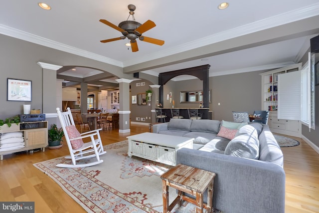 living room with a ceiling fan, recessed lighting, decorative columns, crown molding, and wood finished floors