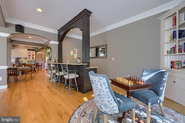 dining area with ornamental molding, arched walkways, and light wood-style floors