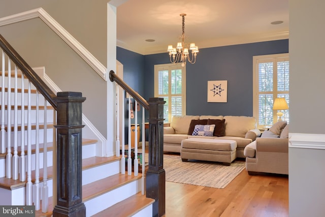 living area with an inviting chandelier, wood finished floors, and stairs