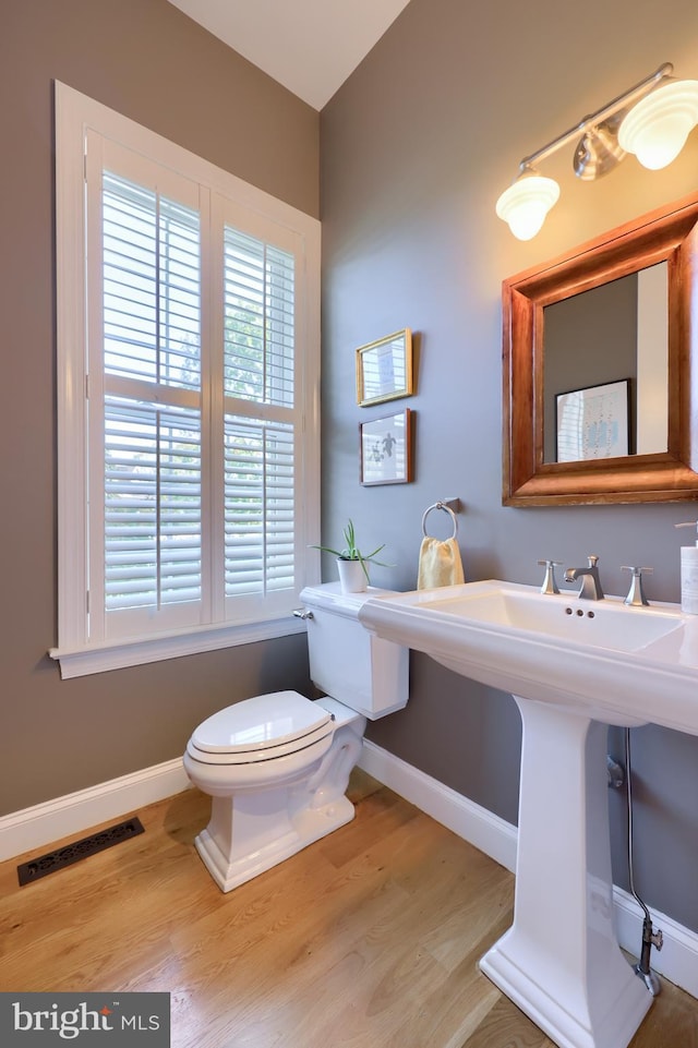 bathroom with wood finished floors, visible vents, baseboards, and toilet