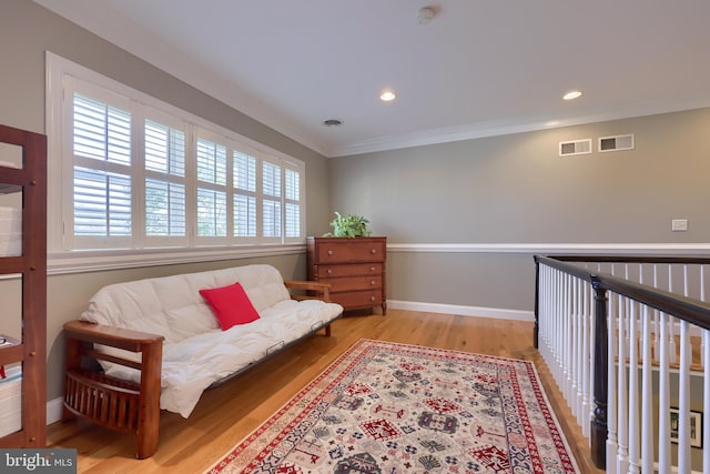living area with ornamental molding, baseboards, visible vents, and wood finished floors