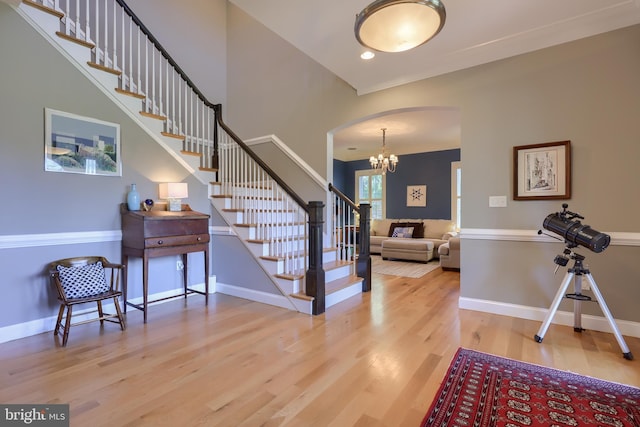 foyer featuring wood finished floors, baseboards, arched walkways, and stairs