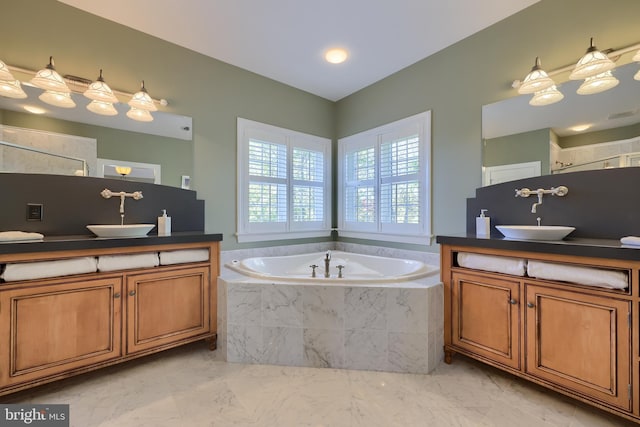 bathroom with a sink, two vanities, and a garden tub