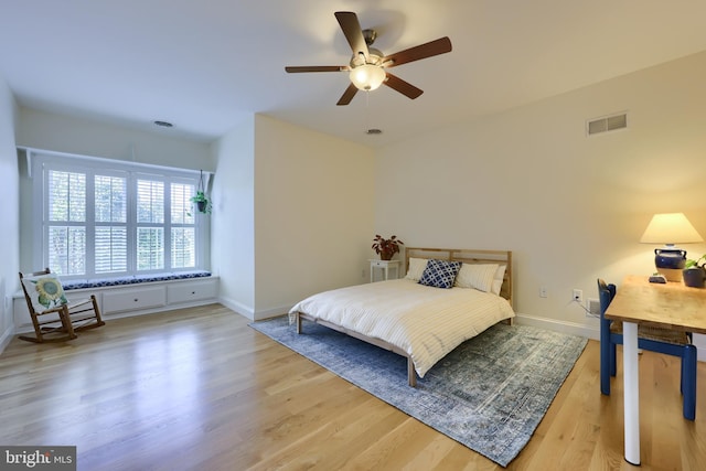 bedroom with baseboards, a ceiling fan, visible vents, and wood finished floors