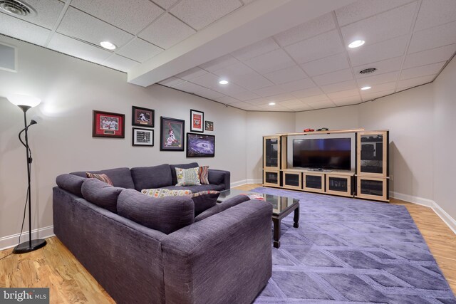 living area featuring baseboards, a drop ceiling, visible vents, and wood finished floors