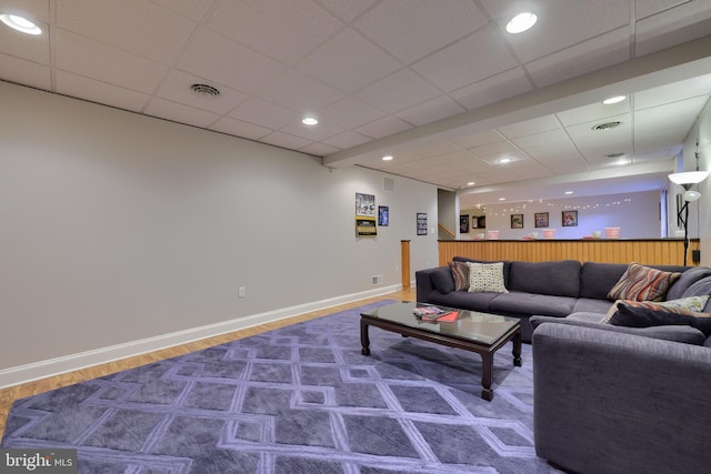 living room with visible vents, wood finished floors, baseboards, and a paneled ceiling