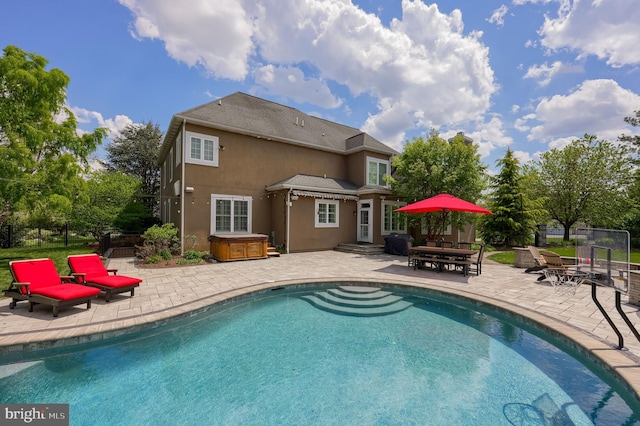 view of pool with a patio area, a hot tub, and fence
