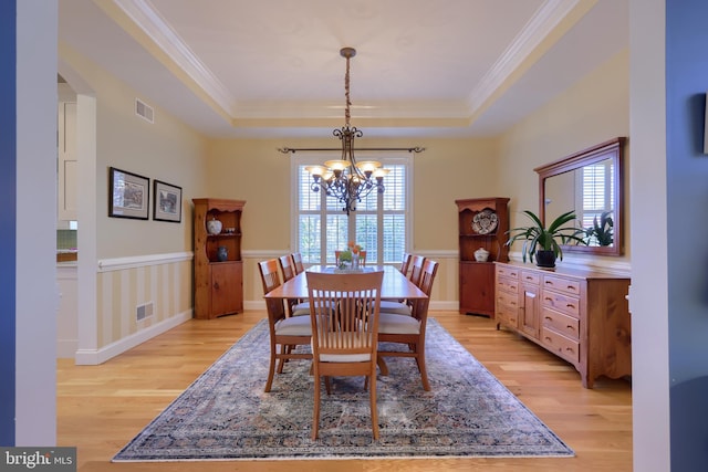dining space featuring visible vents, crown molding, a chandelier, light wood finished floors, and arched walkways