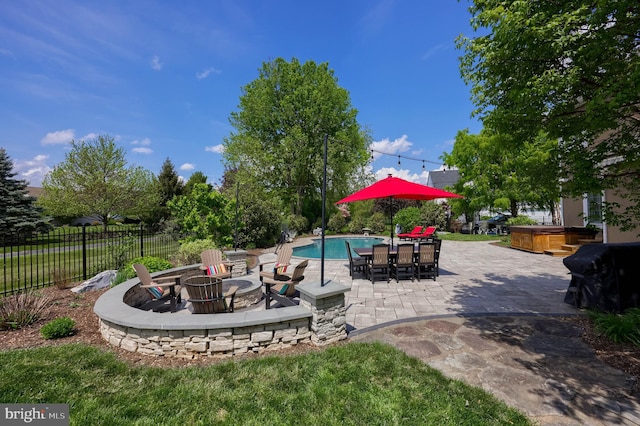 view of patio with an outdoor fire pit, a hot tub, fence, and a fenced in pool