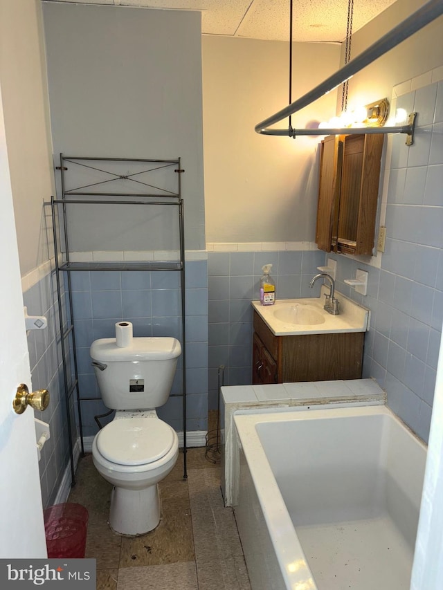 bathroom with tile walls, tile patterned flooring, vanity, and toilet