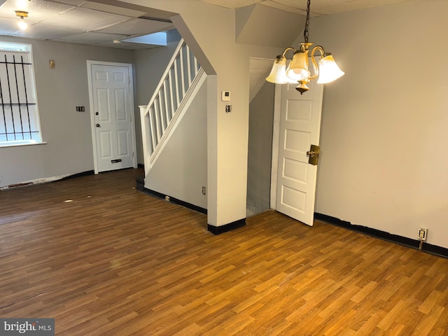 empty room with hardwood / wood-style floors and a notable chandelier