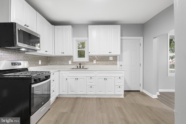 kitchen featuring tasteful backsplash, sink, light hardwood / wood-style floors, stainless steel appliances, and white cabinets