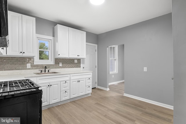 kitchen with electric range oven, sink, light hardwood / wood-style flooring, and tasteful backsplash