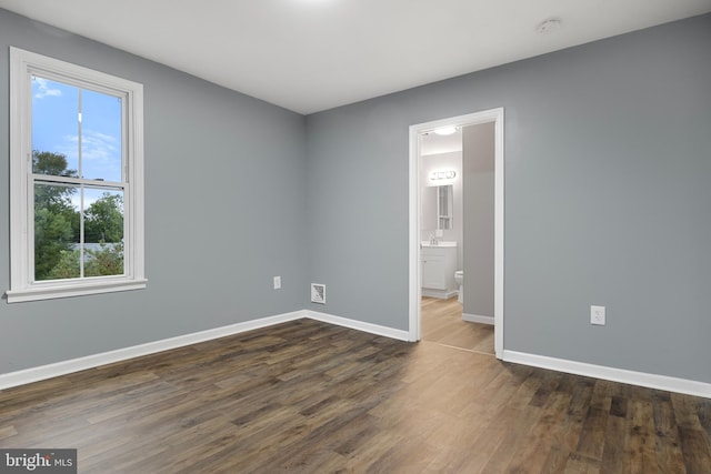 unfurnished bedroom featuring ensuite bathroom and dark wood-type flooring