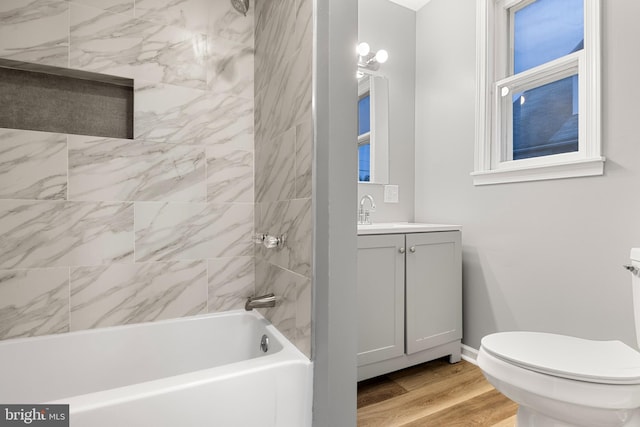 full bathroom featuring vanity, tiled shower / bath combo, hardwood / wood-style flooring, and toilet