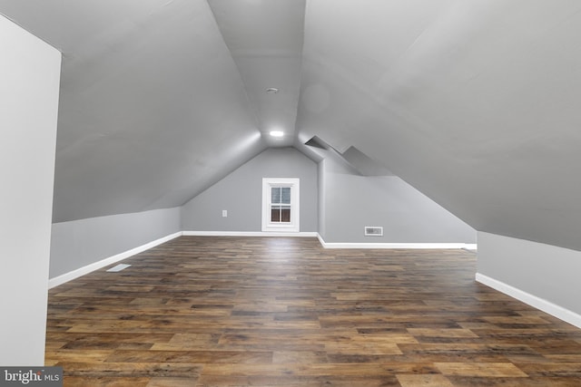 additional living space with vaulted ceiling and dark hardwood / wood-style flooring