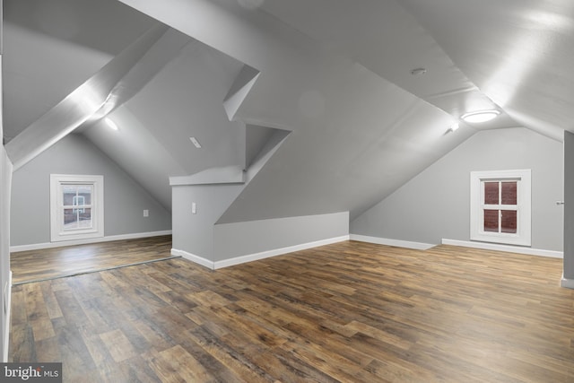 additional living space featuring dark wood-type flooring and vaulted ceiling