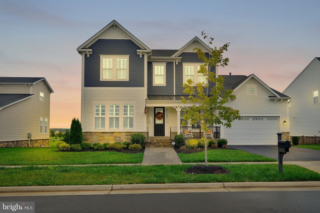 craftsman inspired home with a garage and a yard