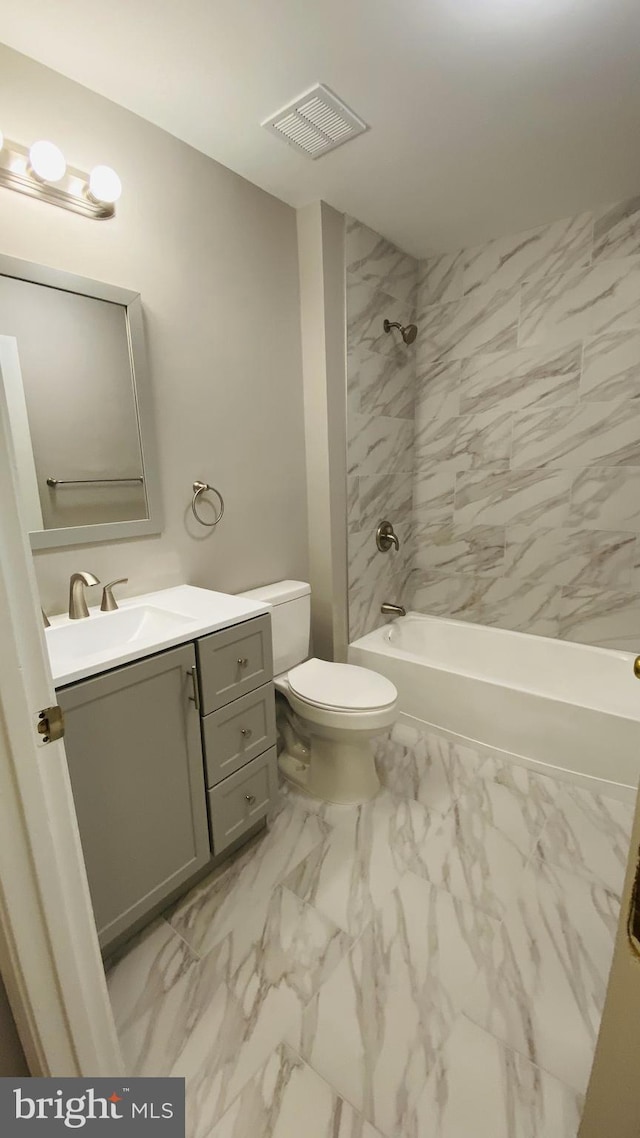 full bathroom with tiled shower / bath, vanity, and toilet