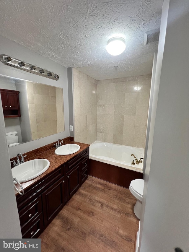 bathroom featuring vanity, hardwood / wood-style flooring, a bathtub, toilet, and a textured ceiling