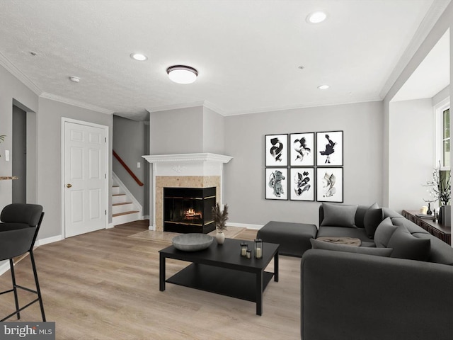 living room with crown molding, light hardwood / wood-style floors, and a tile fireplace