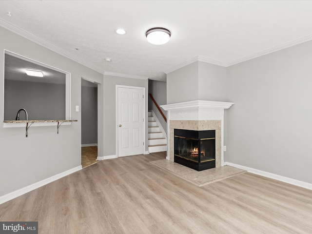 unfurnished living room with a multi sided fireplace, light wood-type flooring, and crown molding