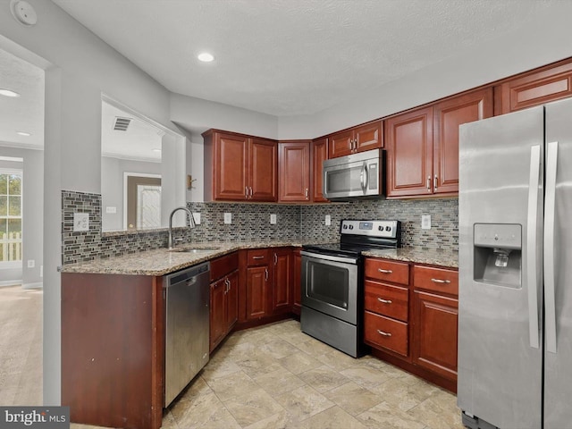 kitchen featuring sink, tasteful backsplash, a textured ceiling, appliances with stainless steel finishes, and light stone countertops