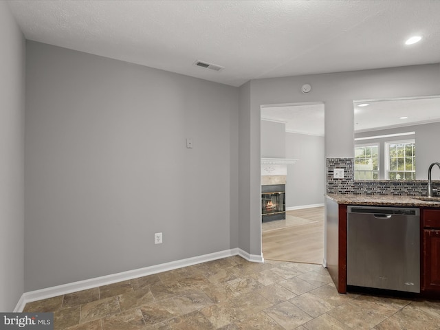 kitchen featuring tasteful backsplash, sink, stainless steel dishwasher, and a textured ceiling