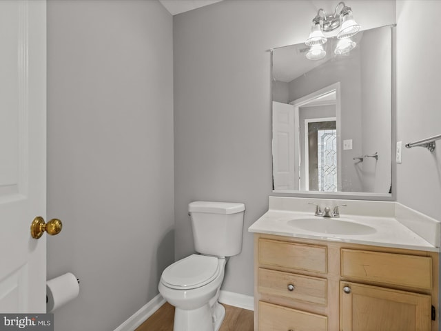 bathroom featuring hardwood / wood-style floors, an inviting chandelier, vanity, and toilet