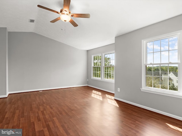 empty room featuring lofted ceiling, dark hardwood / wood-style floors, and a wealth of natural light