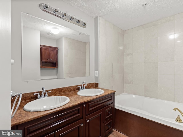 bathroom featuring a bath, vanity, and a textured ceiling