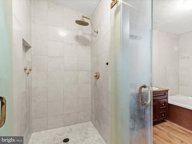 bathroom with vanity, shower with separate bathtub, hardwood / wood-style floors, and a textured ceiling