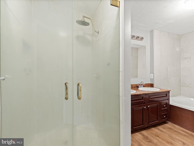 bathroom featuring separate shower and tub, vanity, wood-type flooring, and a textured ceiling