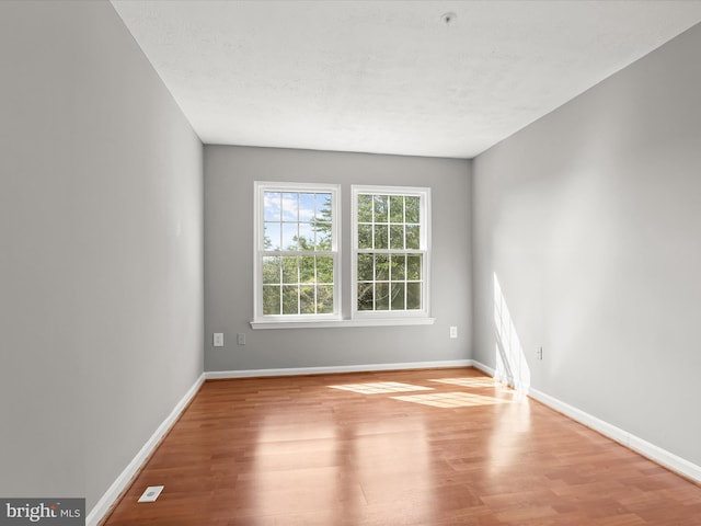 empty room featuring a textured ceiling and light hardwood / wood-style flooring