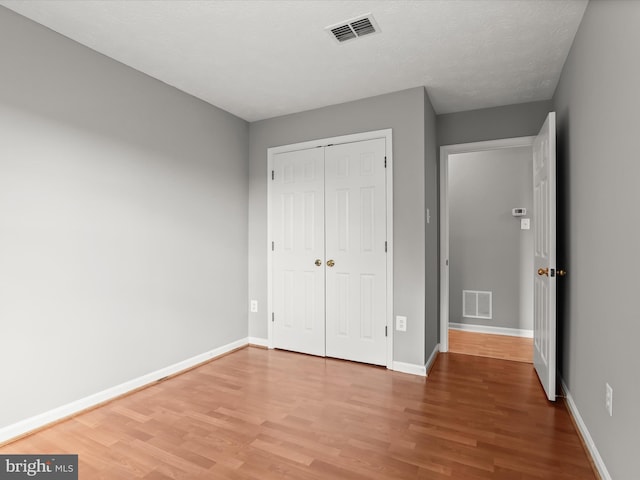 unfurnished bedroom featuring hardwood / wood-style flooring, a closet, and a textured ceiling