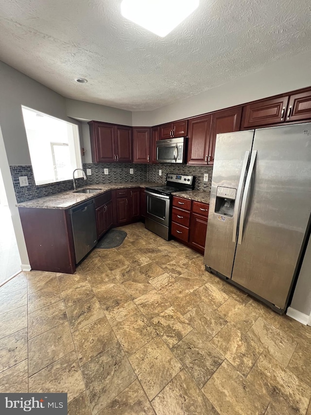 kitchen featuring a textured ceiling, stainless steel appliances, sink, and tasteful backsplash