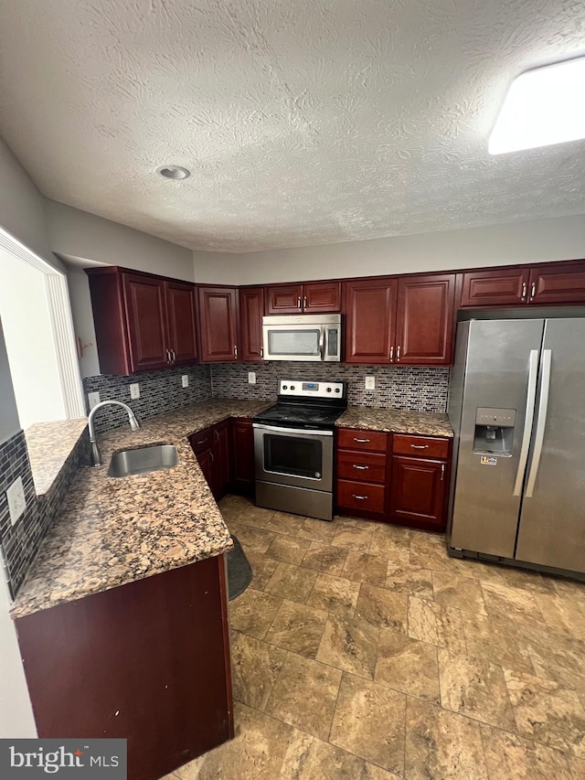 kitchen with dark stone countertops, sink, backsplash, appliances with stainless steel finishes, and a textured ceiling