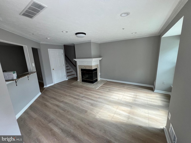 unfurnished living room featuring hardwood / wood-style flooring, crown molding, a multi sided fireplace, and a textured ceiling