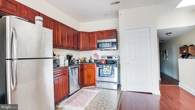 kitchen with appliances with stainless steel finishes and dark hardwood / wood-style floors