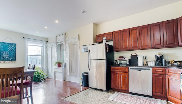 kitchen featuring stainless steel appliances, dark stone counters, and light hardwood / wood-style flooring